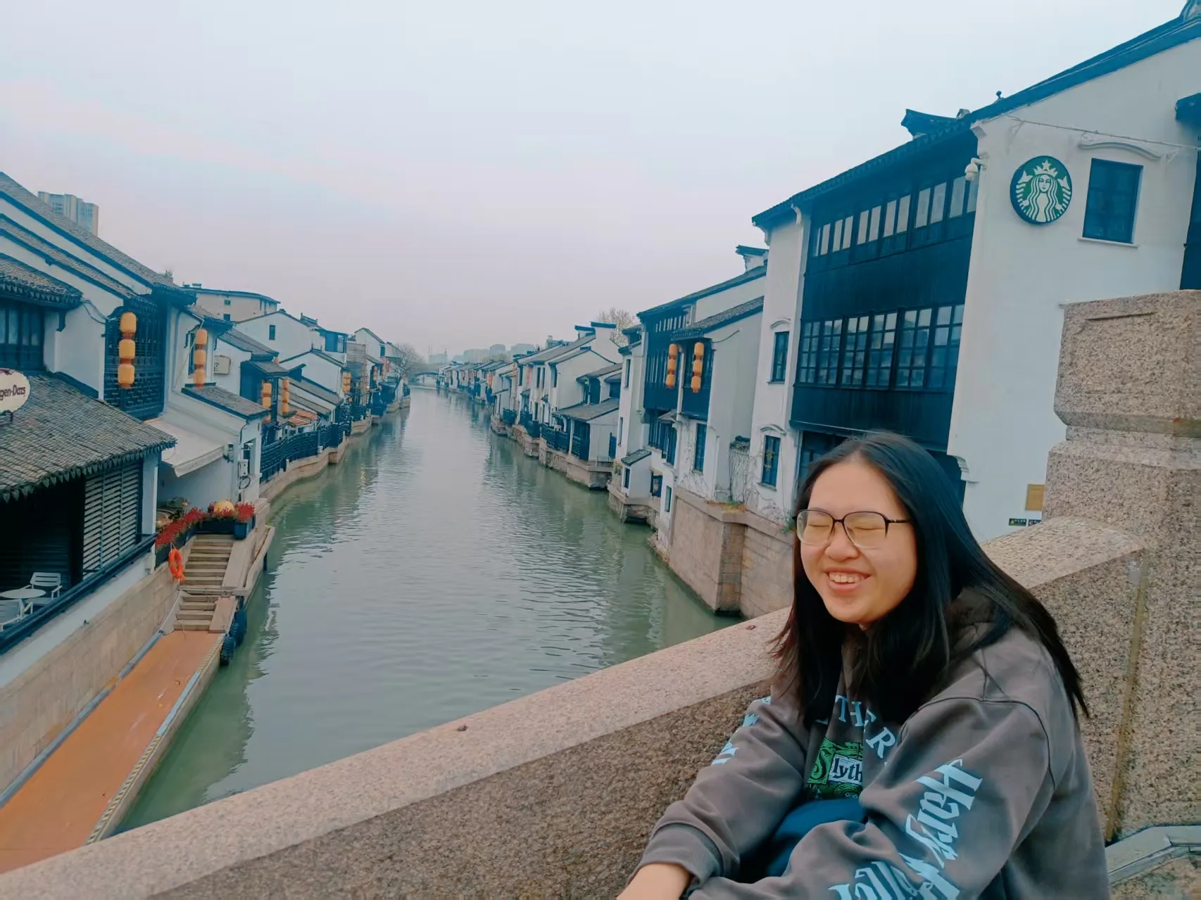 朋友的抓拍：我在桥上，背景是小河与河岸边古色古香的建筑